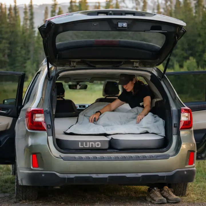 Woman setting up a Luno mattress inside an SUV for a clean, comfortable car camping sleep setup