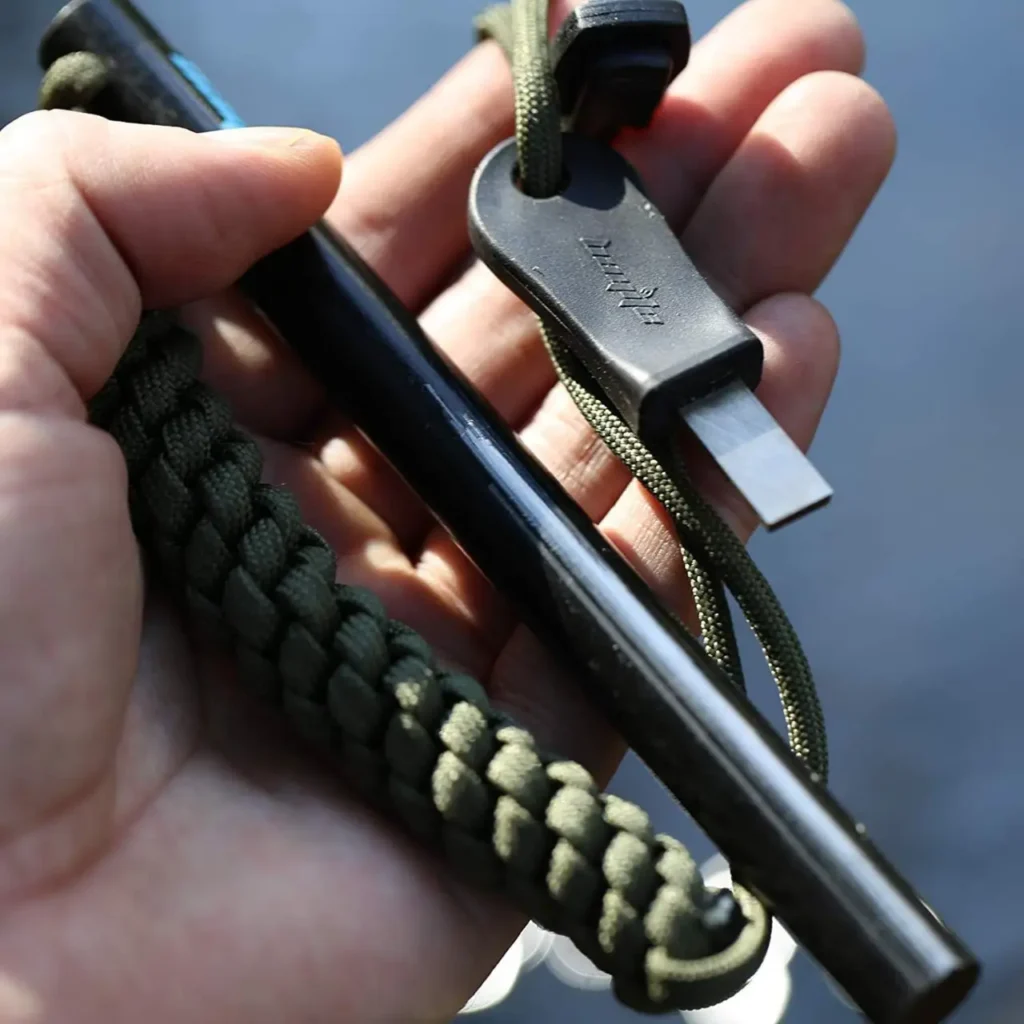Close-up of a firesteel with paracord and striker held in hand for a camping and hiking fire starter review