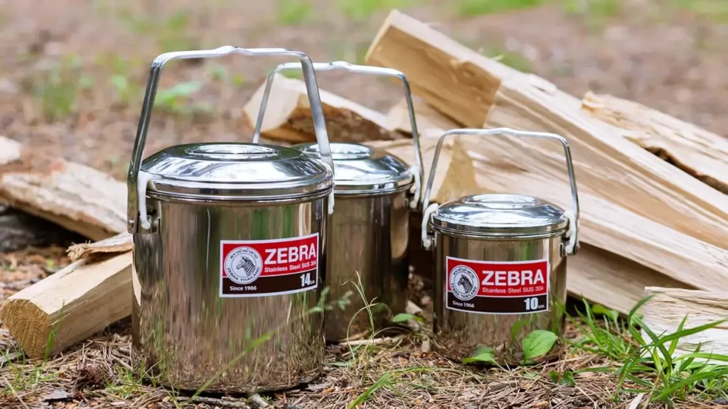 Zebra Loop Handle Pot in multiple sizes displayed at camp beside stacked firewood