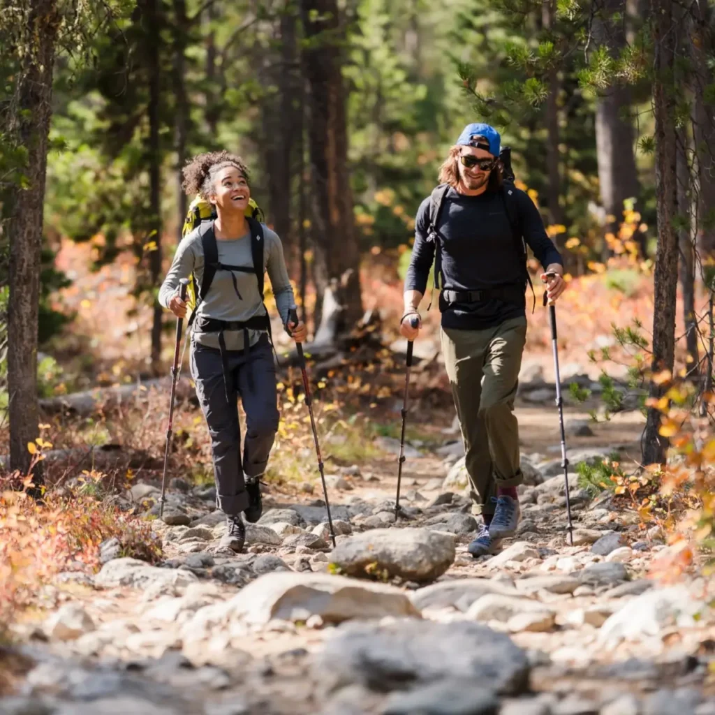 Two hikers using Black Diamond Trail Back Trekking Poles on a rocky forest trail.
