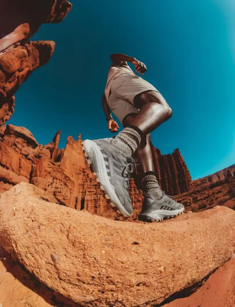 Merrell Moab Speed 2 hiking shoes on a hiker walking across red desert rocks for a beginner hiking shoes guide.