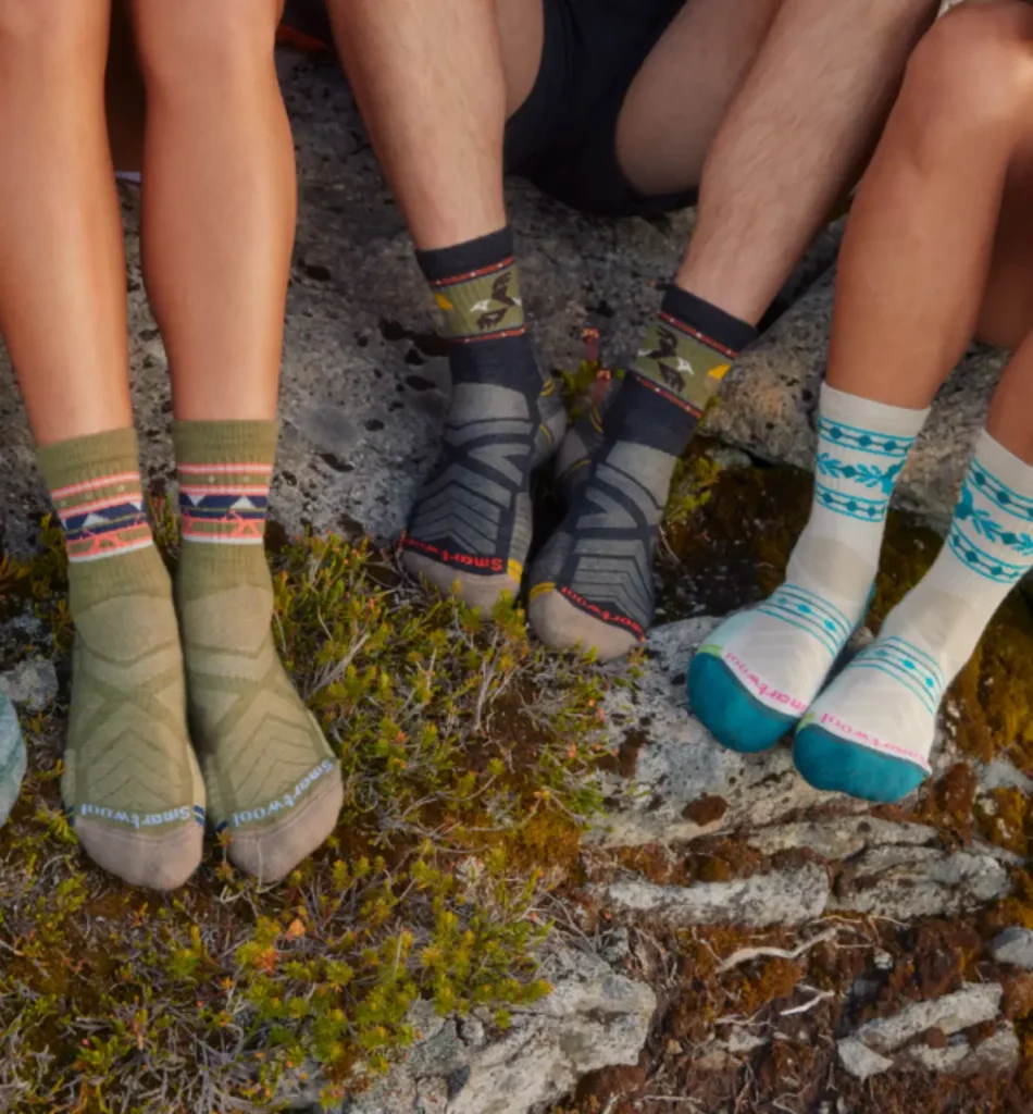 Smartwool Performance Hike Light Cushion Crew hiking socks worn by hikers sitting on rocky terrain, featured in a guide to the best hiking socks for blister prevention.