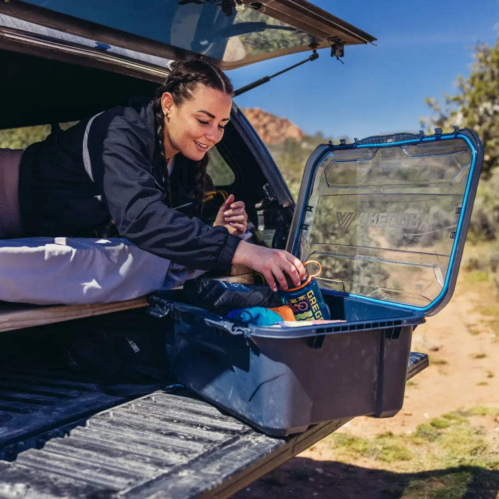 Camper organizing cooking supplies inside a Gregory Alpaca Gear Box 45 at the back of an SUV.