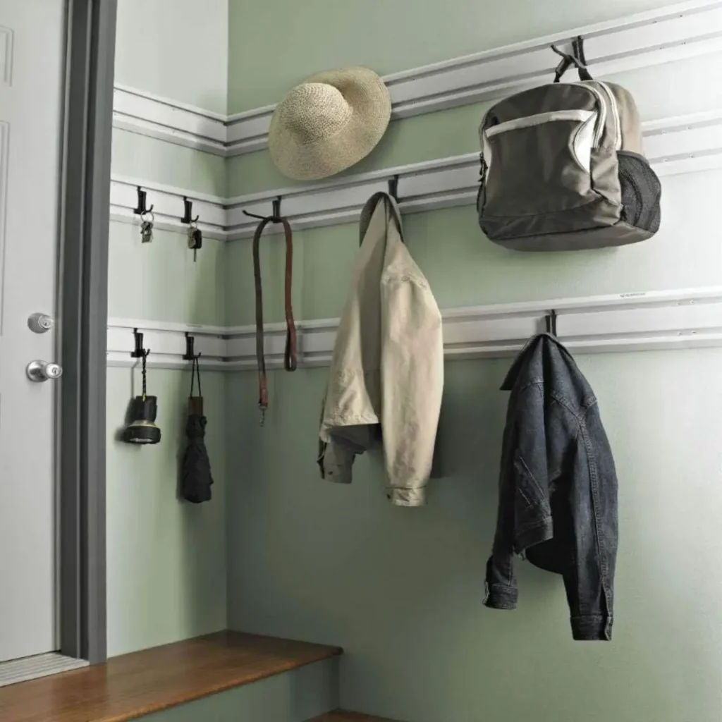Wall-mounted small-space outdoor gear storage system holding a backpack, jackets, hat, keys, and compact outdoor accessories.