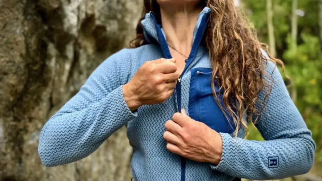 Woman wearing a Patagonia R1 Air Full-Zip Hoody as a fleece mid layer on a wooded trail, illustrating a practical fall hiking layering system.