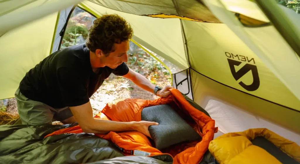 Camper setting up a NEMO Fillo pillow inside a tent with a sleeping bag.